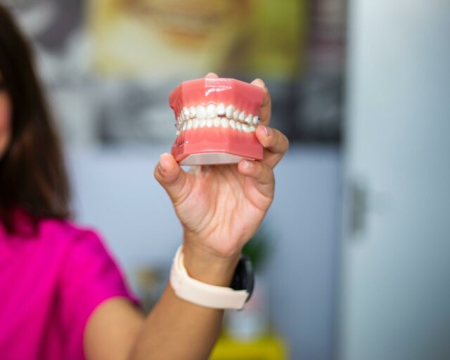 left hand holding false teeth