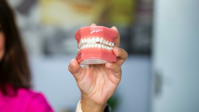left hand holding false teeth