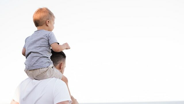 a child on a dads shoulders