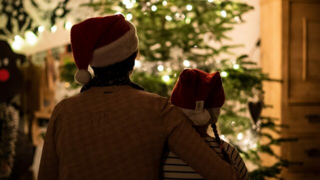 2 people sat in front of a christmas tree