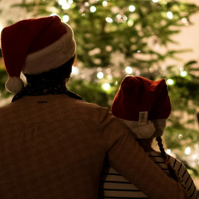 2 people sat in front of a christmas tree